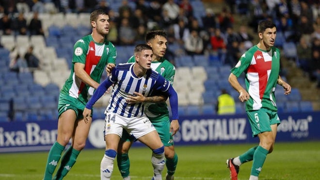 David del Pozo sujetado por dos adversarios del Alcoyano