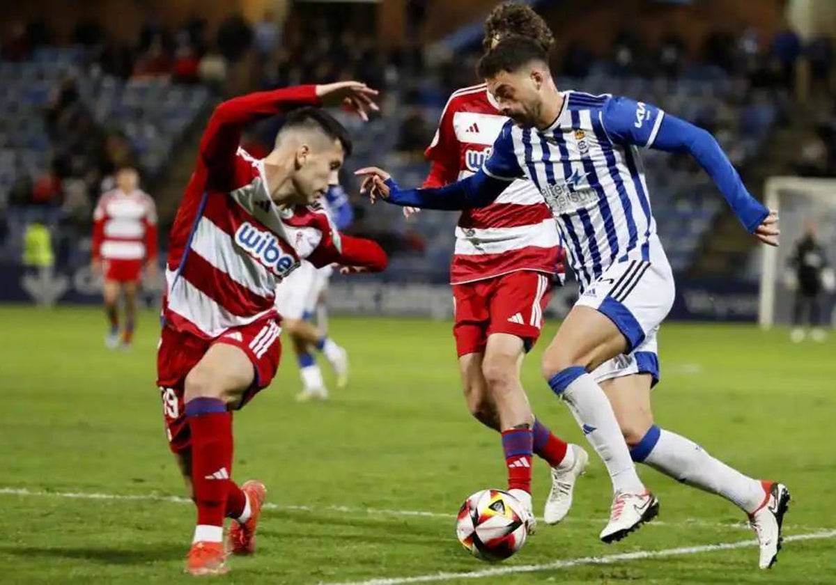 Luis Alcalde encarando a dos rivales durante el Recreativo de Huelva-Recreativo Granada