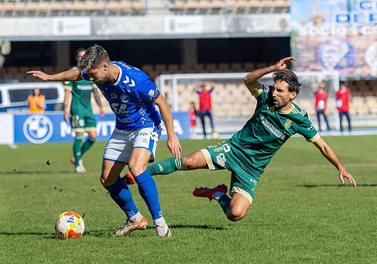 Álex Bernal cae al césped de Chapín ante un rival durante el Xerez DFC-Recreativo de Huelva
