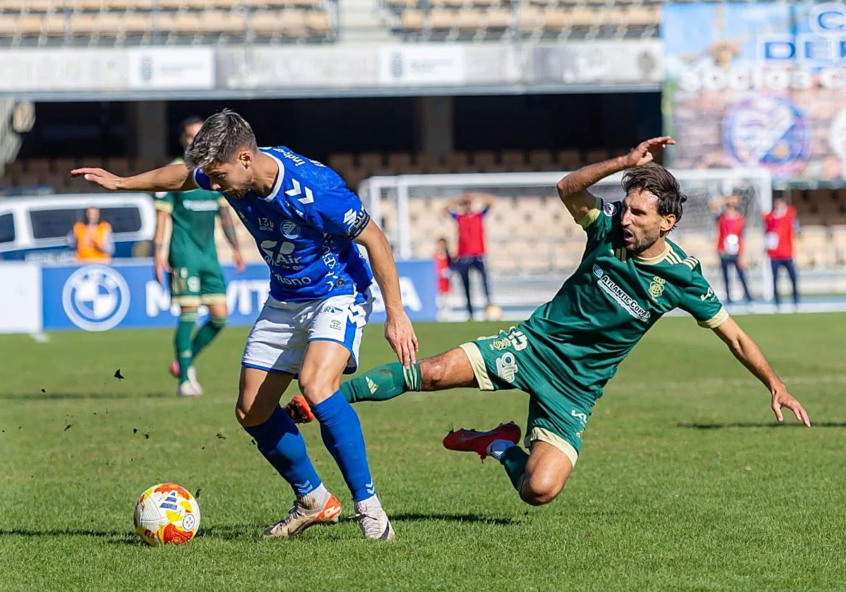 Álex Bernal cae al césped de Chapín ante un rival durante el Xerez DFC-Recreativo de Huelva
