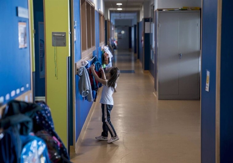 Una niña colocando una mochila en su colegio de Huelva