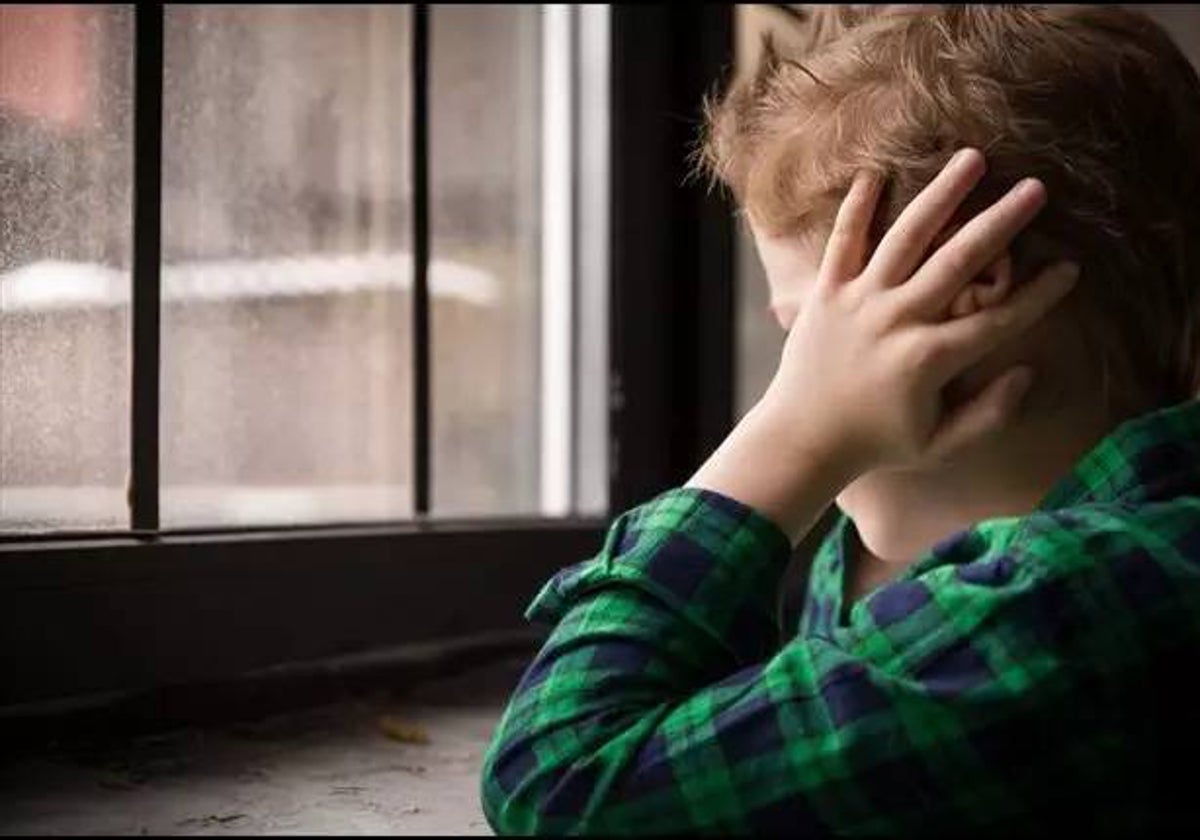 Un niño asustado mirando por la ventana