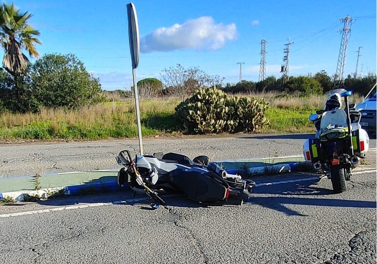 La moto que llevaba la droga, tirada en el asfalto junto a una patrulla de la Guardia Civil