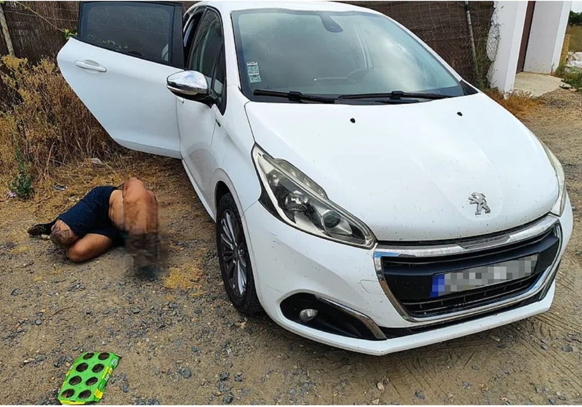La víctima junto al vehículo donde fue encontrado en el término municipal de Lepe