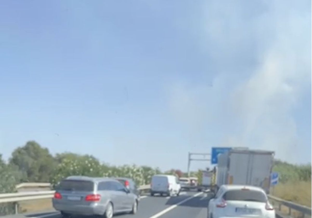 Atasco en la A-49 con una columna de humo al fondo