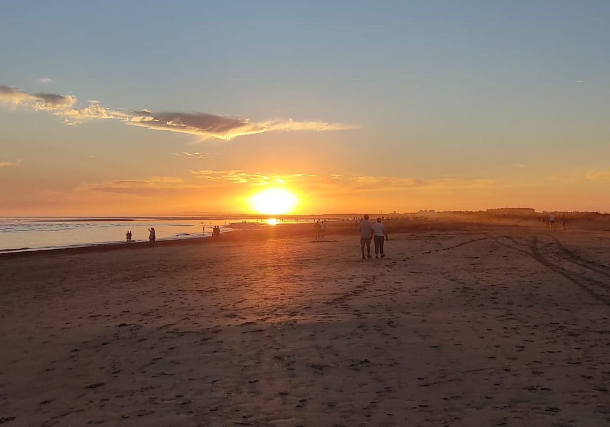 Algunas personas pasean por la playa de la Bota, en la provincia de Huelva