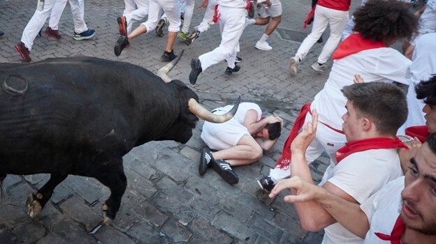 Un joven se protege ante un toro de Cebada Gago durante el encierro
