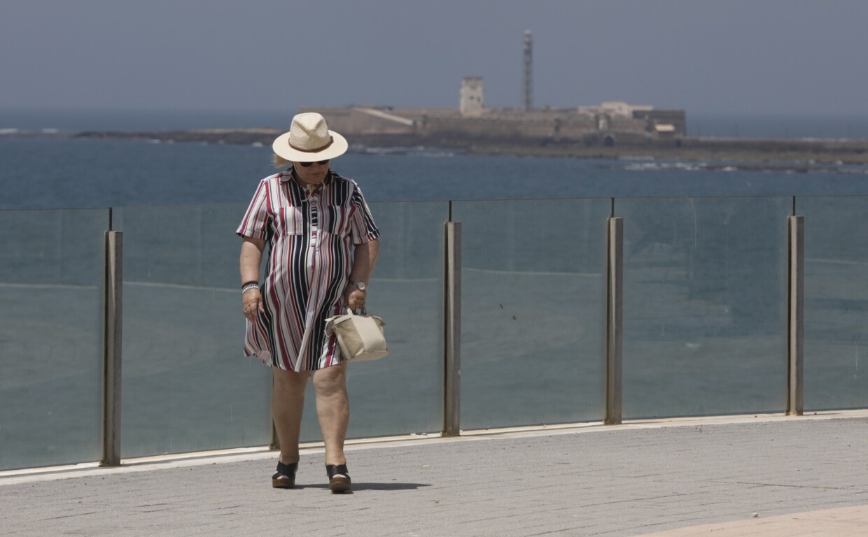 Una mujer camina por el paseo marítimo de Cádiz.