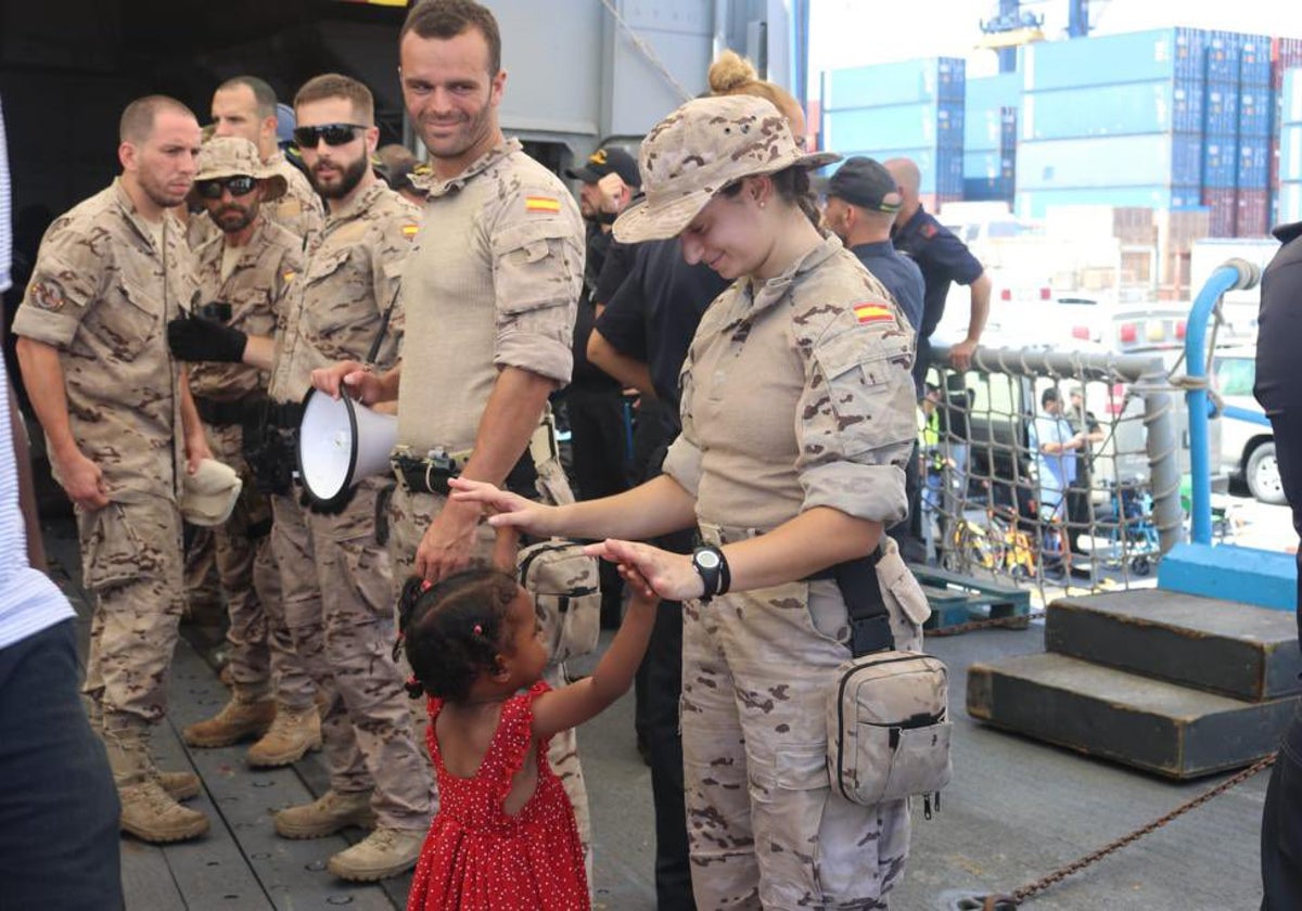 Una militar del equipo de seguridad de Infantería de Marina embarcado en la fragata juega con una niña durante la evacuación.