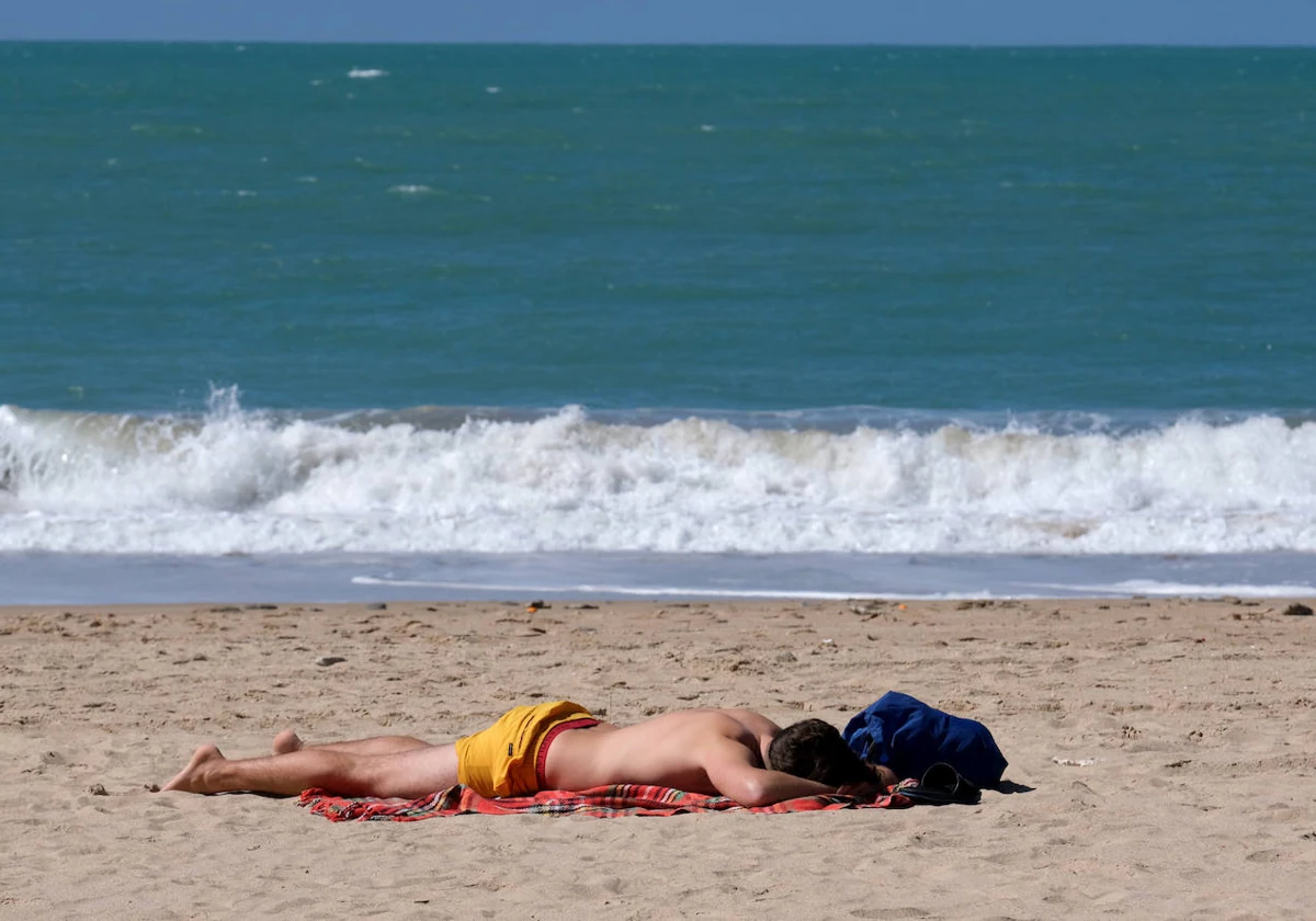 Un bañista toma el sol en la playa de La Victoria en Cádiz.
