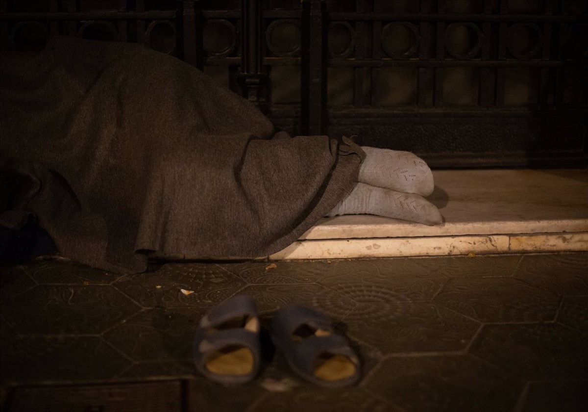 Un hombre sin hogar duerme en la calle.