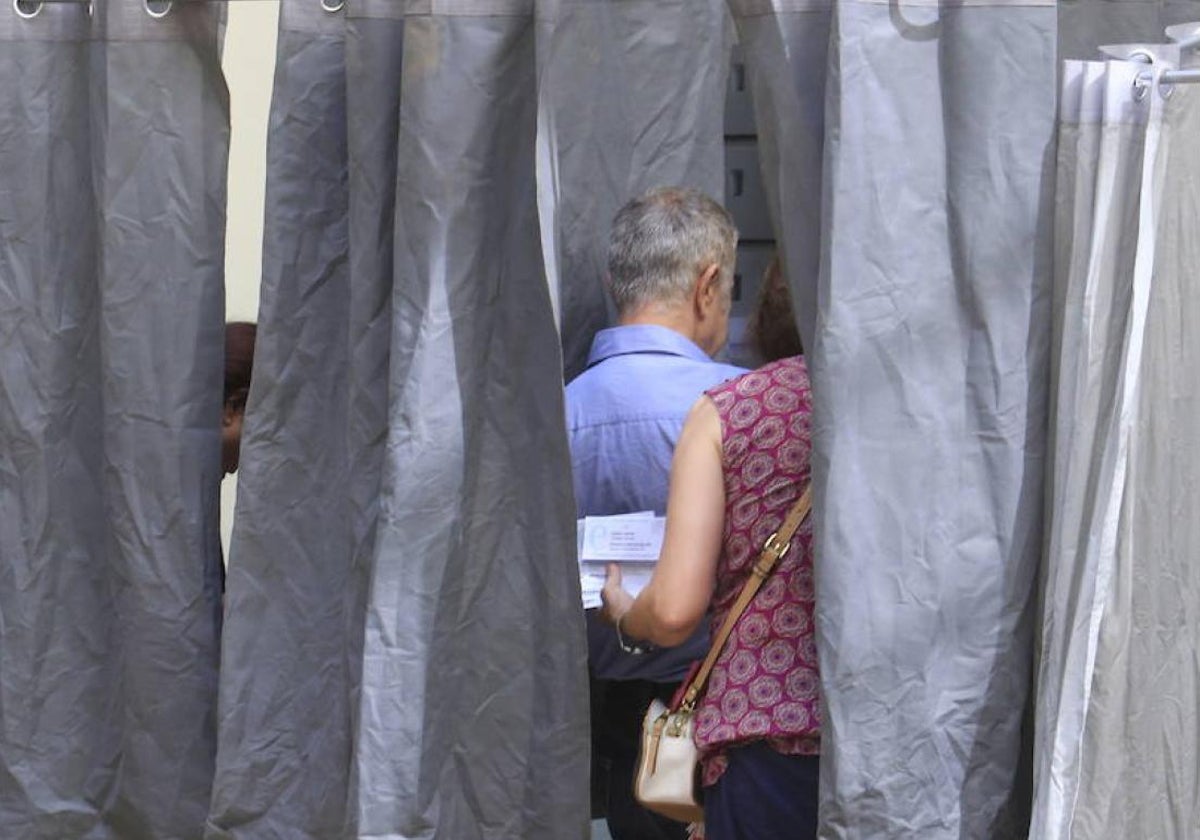 Dos electores utilizan una de las cabinas para elegir la candidatura