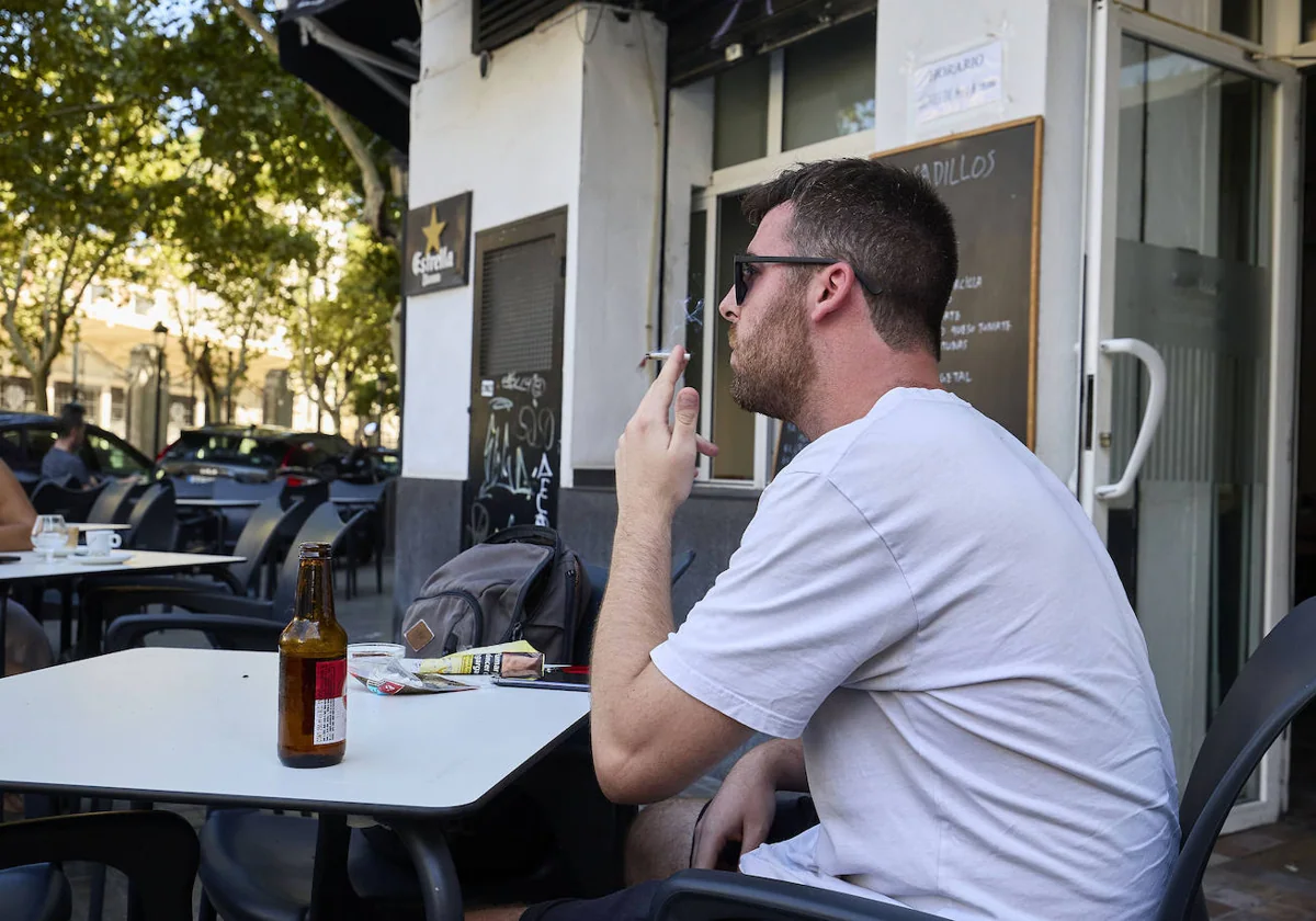 Un joven se fuma un cigarro en una terraza
