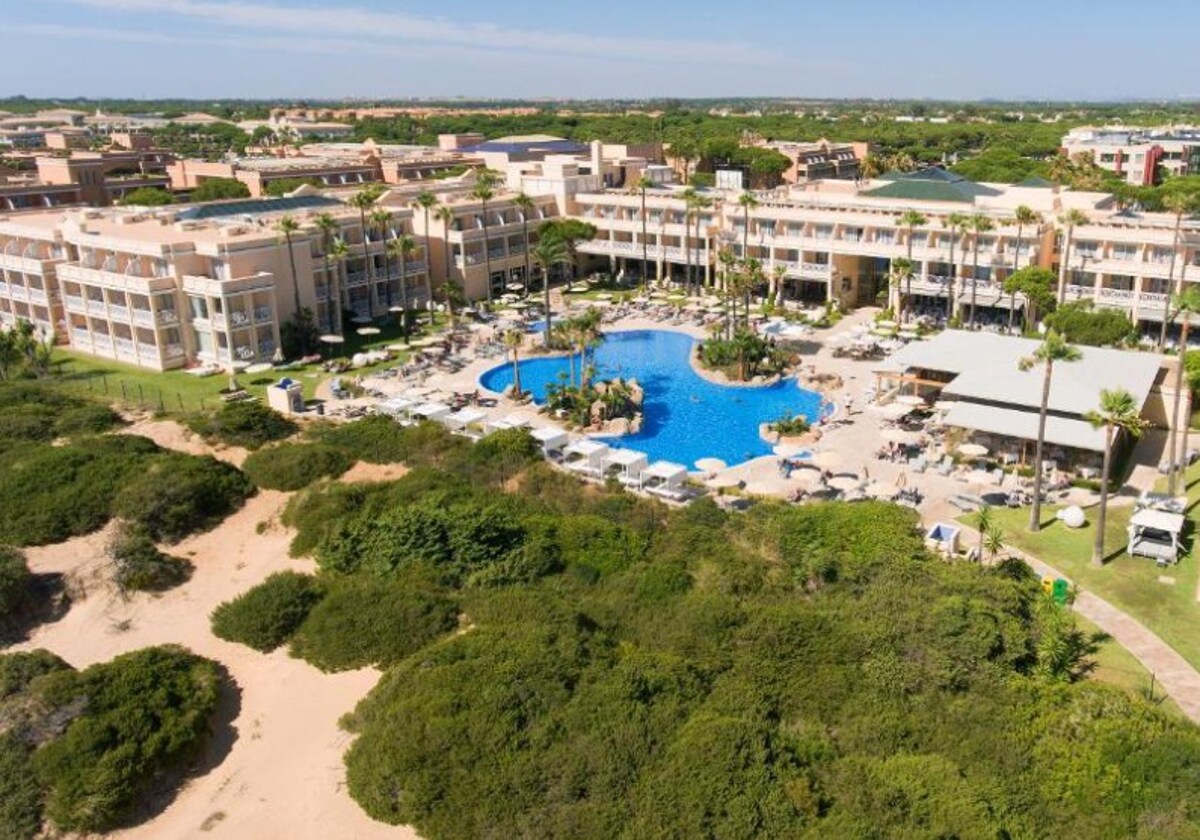 Vista panorámica del hotel con los pinares y arenales de la playa en primer plano