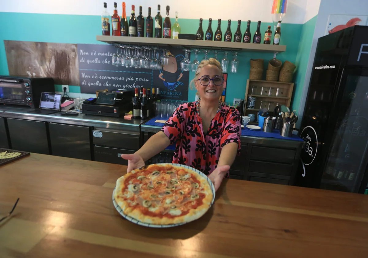 La siempre sonriente Claudia vende una de sus famosas pizzas.
