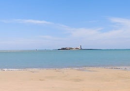 La playa de Cádiz de arena blanca y fina desde la que se puede ver un castillo sobre el mar