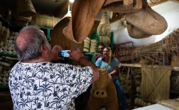 El artesano fotografía a dos clientes subidos en su burro.