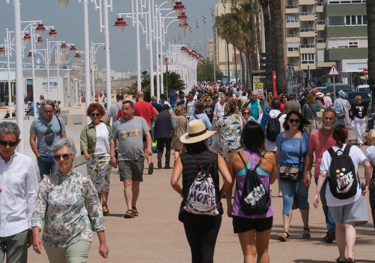 Gente paseando por la capital gaditana junto a la playa Victoria