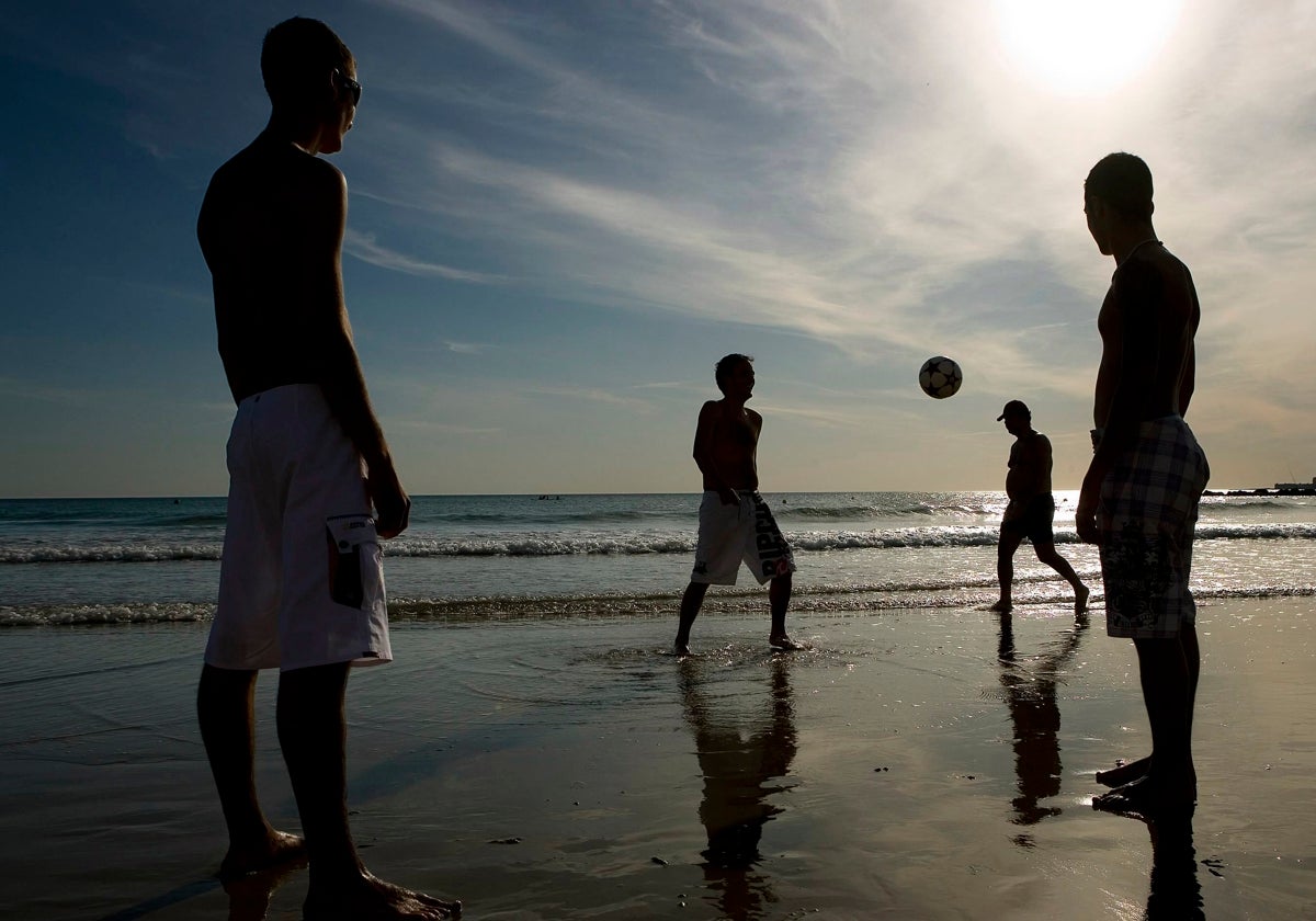 Un grupo de jóvenes juega en la playa.