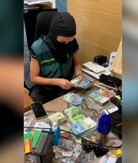 Imagen secundaria 2 - Arriba, Salva y su pareja, en su foto como general capellán y capitana de su orden. Abajo, algunos de los billetes que ofrecían intervenidos. Abajo, una agente cuenta el dinero durante los registros realizados en la operación de la Guardia Civil.