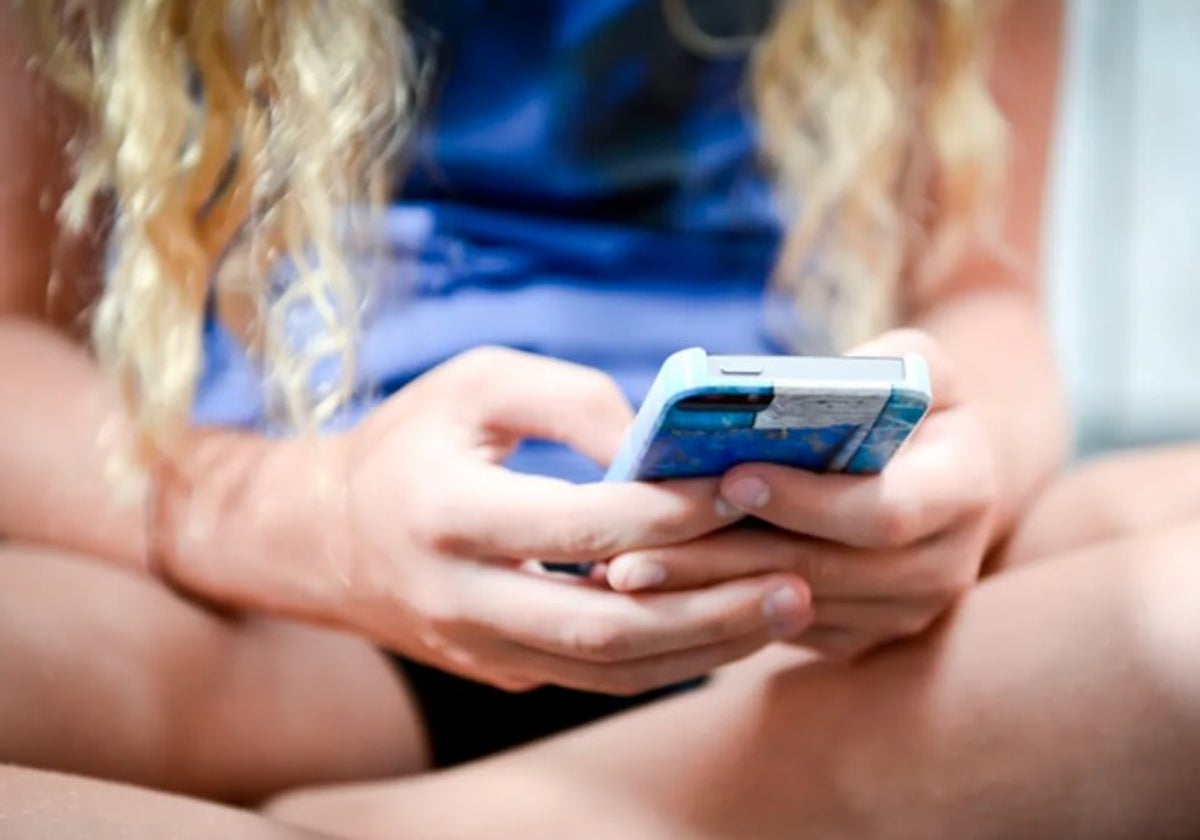 Una adolescente viendo contenido en un teléfono móvil.