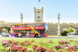 El autobús de City Sightseeing con la Puerta de Tierra de fondo