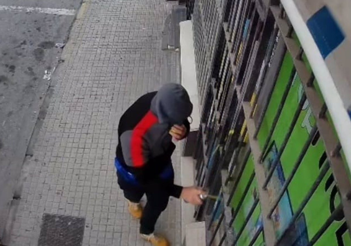 Una persona realizando una pintada de contenido racista en el negocio de un vecino de nacionalidad marroquí de Barbate