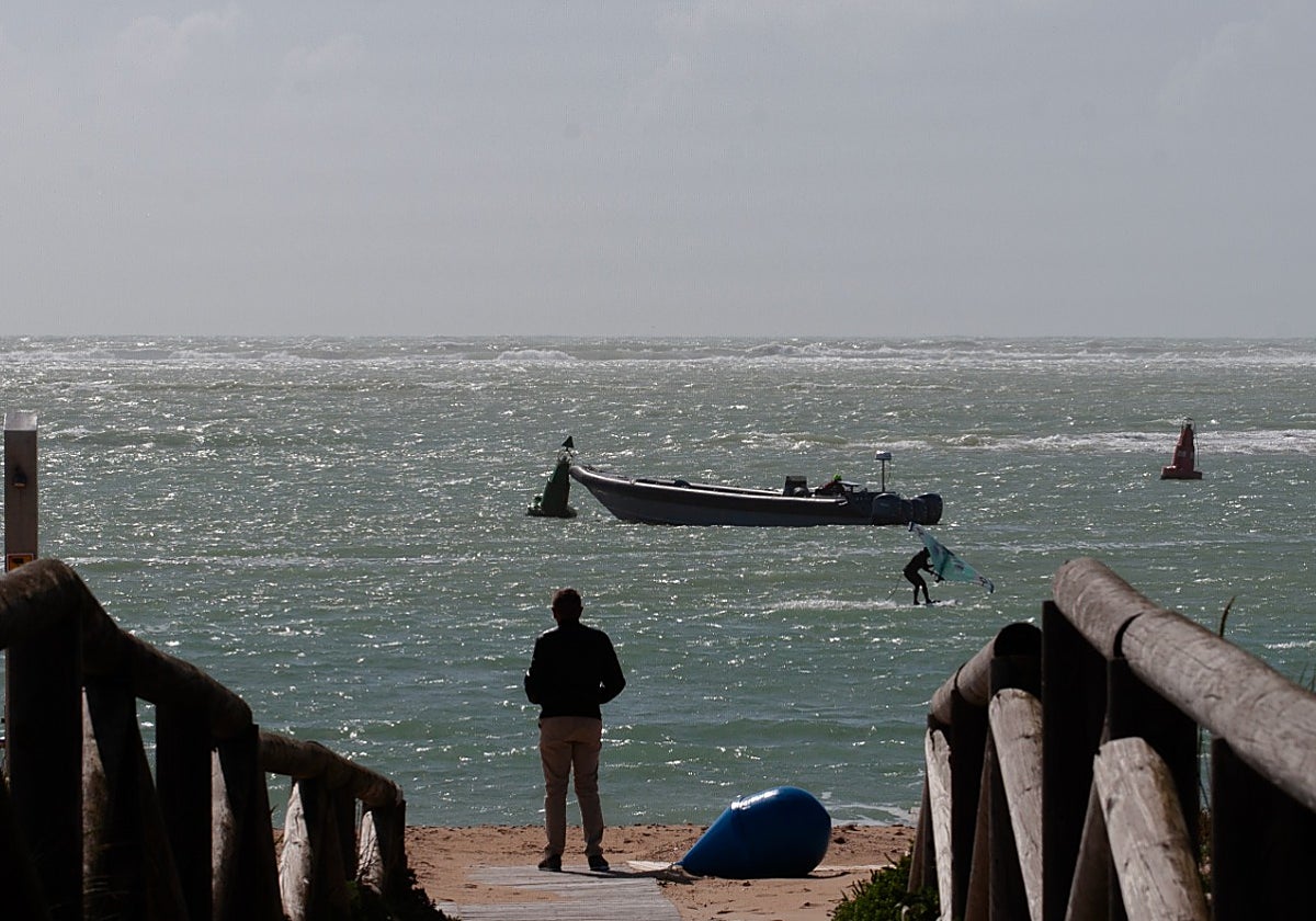 Un vecino de Chiclana observa en Sancti Petri una narcolancha apostada en medio de una competición de kitesurf.