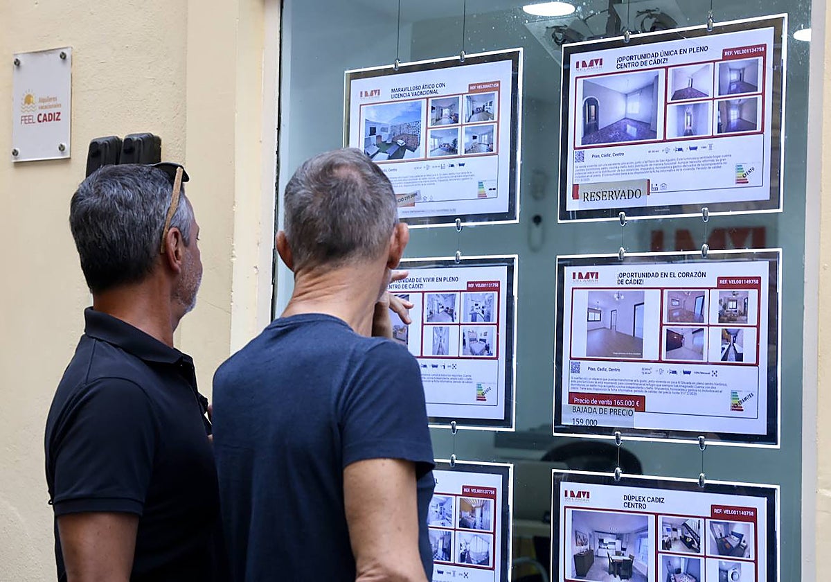 Dos hombres miran los anuncios de una inmobiliaria