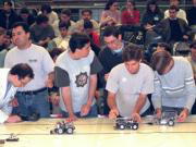 Un grupo de alumnos prepara sus robots antes del toque de salida para que inicien su recorrido por el circuito. Julián de Domingo