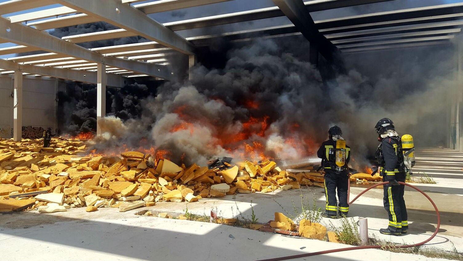 Dos bomberos sofocan las llamas de la fábrica incendiada