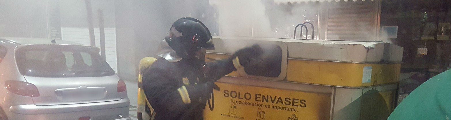 Un bombero sofoca el fuego de un contenedor incendiado intencionadamente