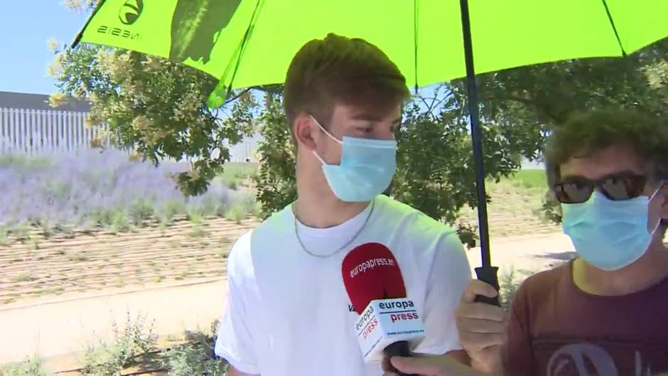 Madrileños se refugian del calor bajo el paraguas mientras esperan ser vacunados