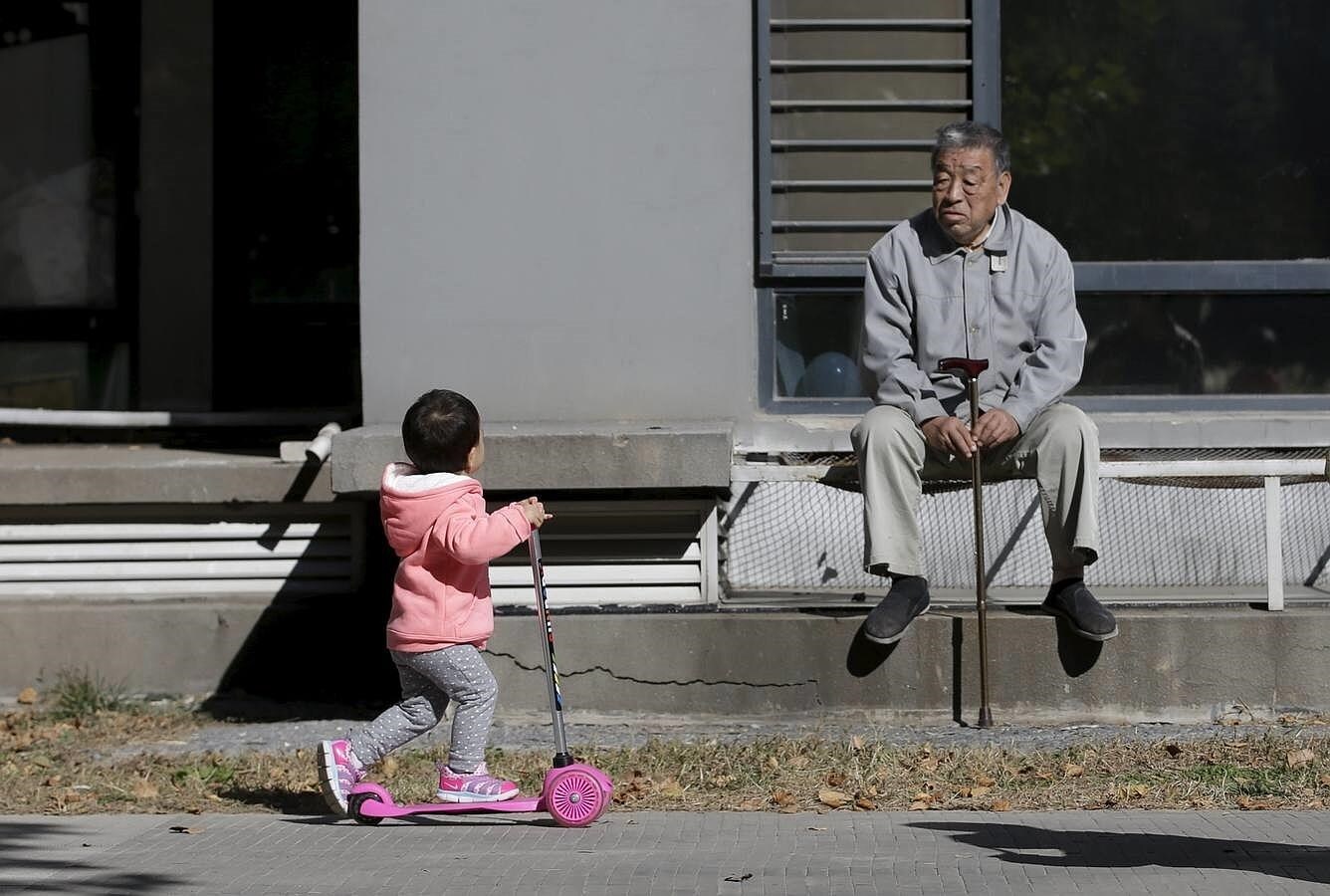 Un anciano de 80 años observa a una niña jugar en Beijing