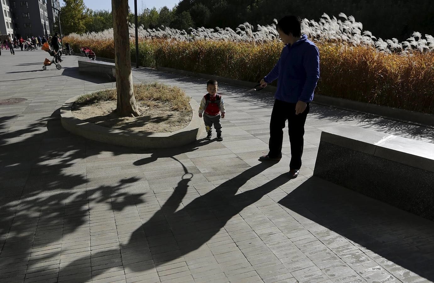 Una mujer jubilada pasea junto a su nieto en una zona residencial de Beijing