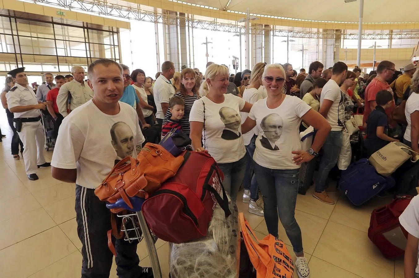 Un grupo de turistas, con camisetas donde se ve la cara del presidente ruso Vladimir Putin, esperan en el aeropuerto de Sharm el-Sheij