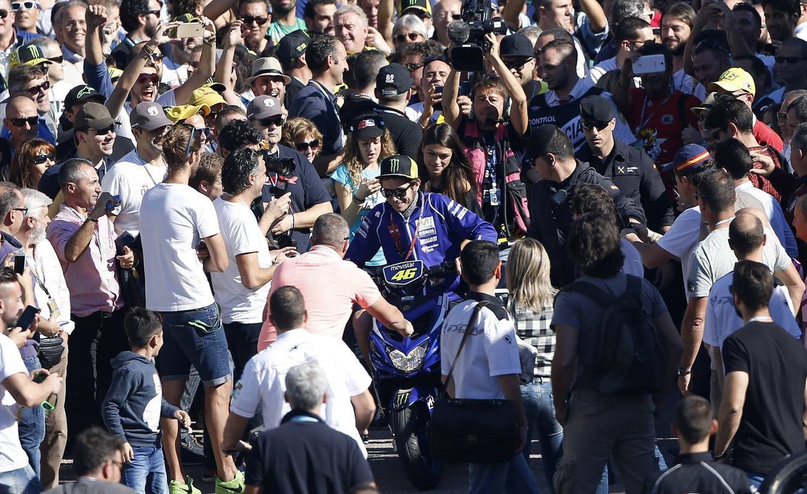 Valentino Rossi intenta abrirse paso ante miles de aficionados en el paddock del circuito Ricardo Tormo