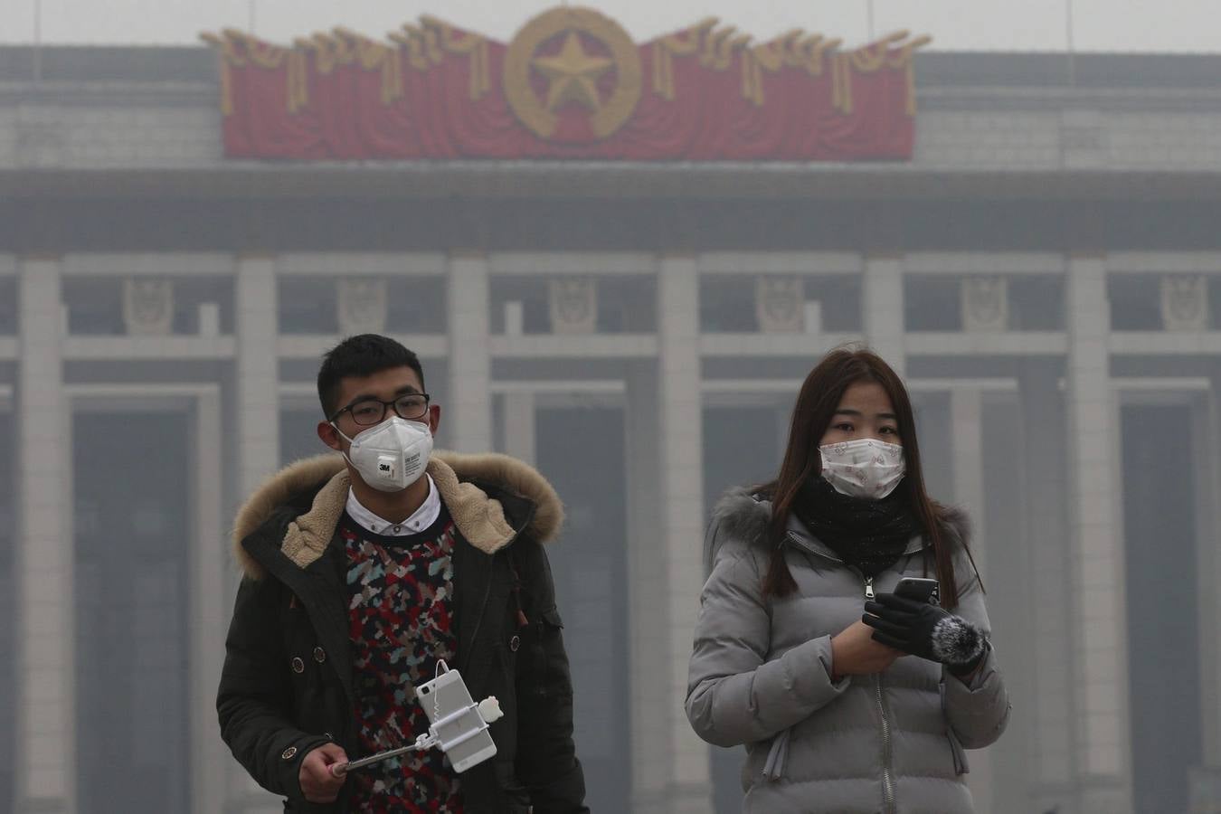 Una pareja usa mascarillas para protegerse de la contaminación ambiental durante una visita a la plaza de Tiananmen en Pekín (China)