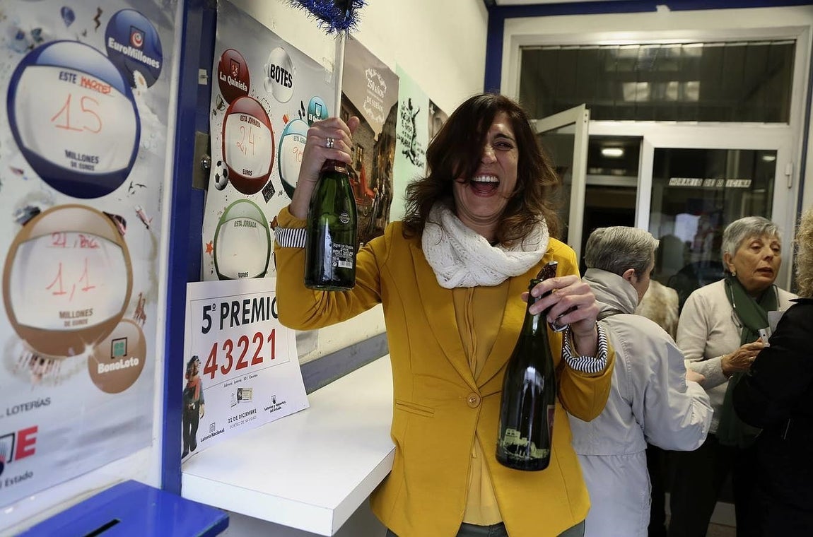 Una empleada de la administración número 30 de Zaragoza, en el barrio rural de Casetas, que ha repartido 900.000 euros del número 43.221, quinto premio de la Lotería Extraordinaria de Navidad, lo celebra con cava. 