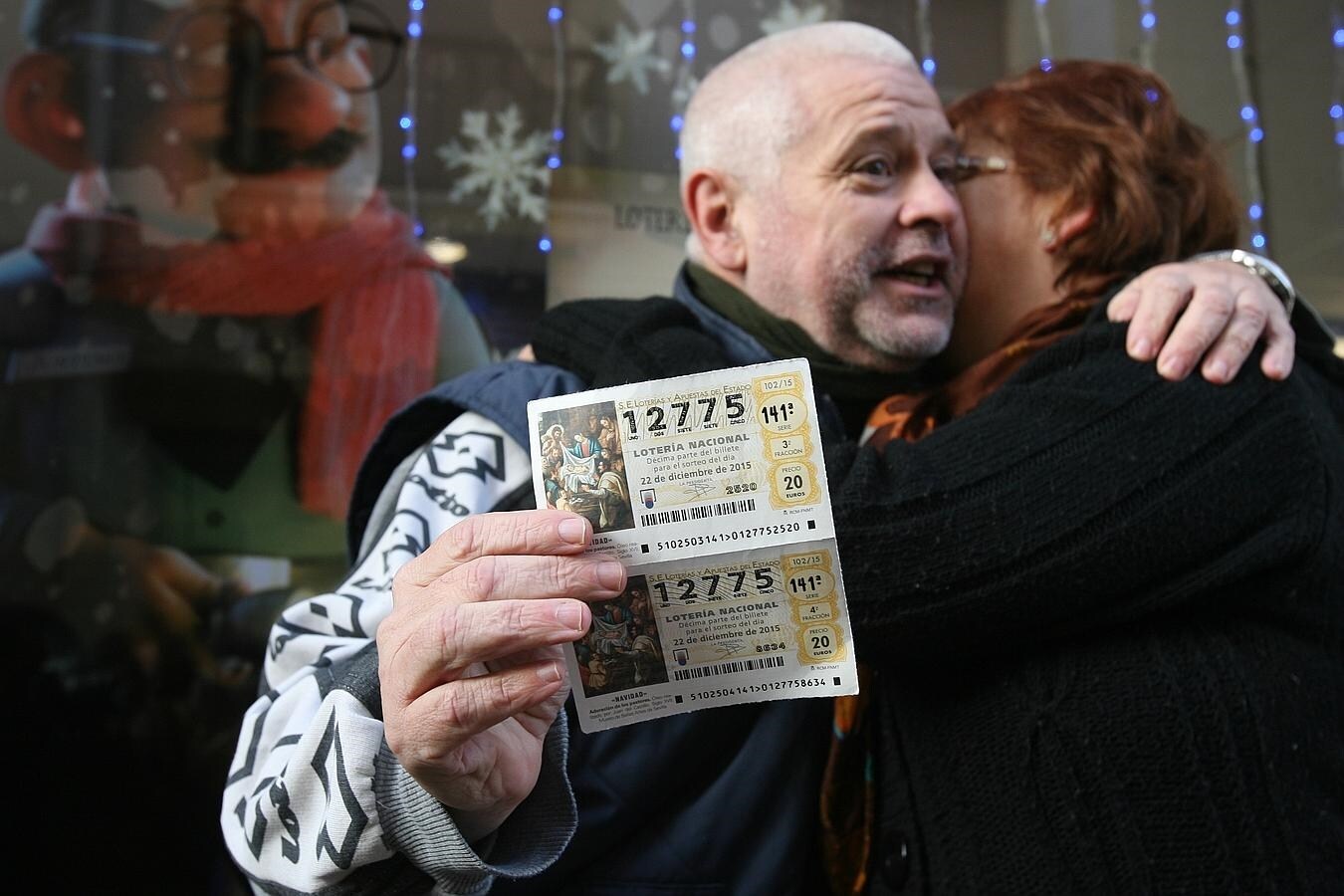 Dos agraciados con el segundo premio de la Loteria de Navidad, el 12.775, se abrazan mientras enseñan los décimos premiados.