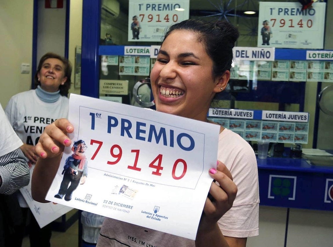 Una joven sonríe con una copia del número 79.140, agraciado con el Gordo de Navidad del Sorteo Extraordinario de la Loteria celebrado hoy y vendido íntegramente en la administracion nº 2 de Roquetas de Mar (Almería).. 
