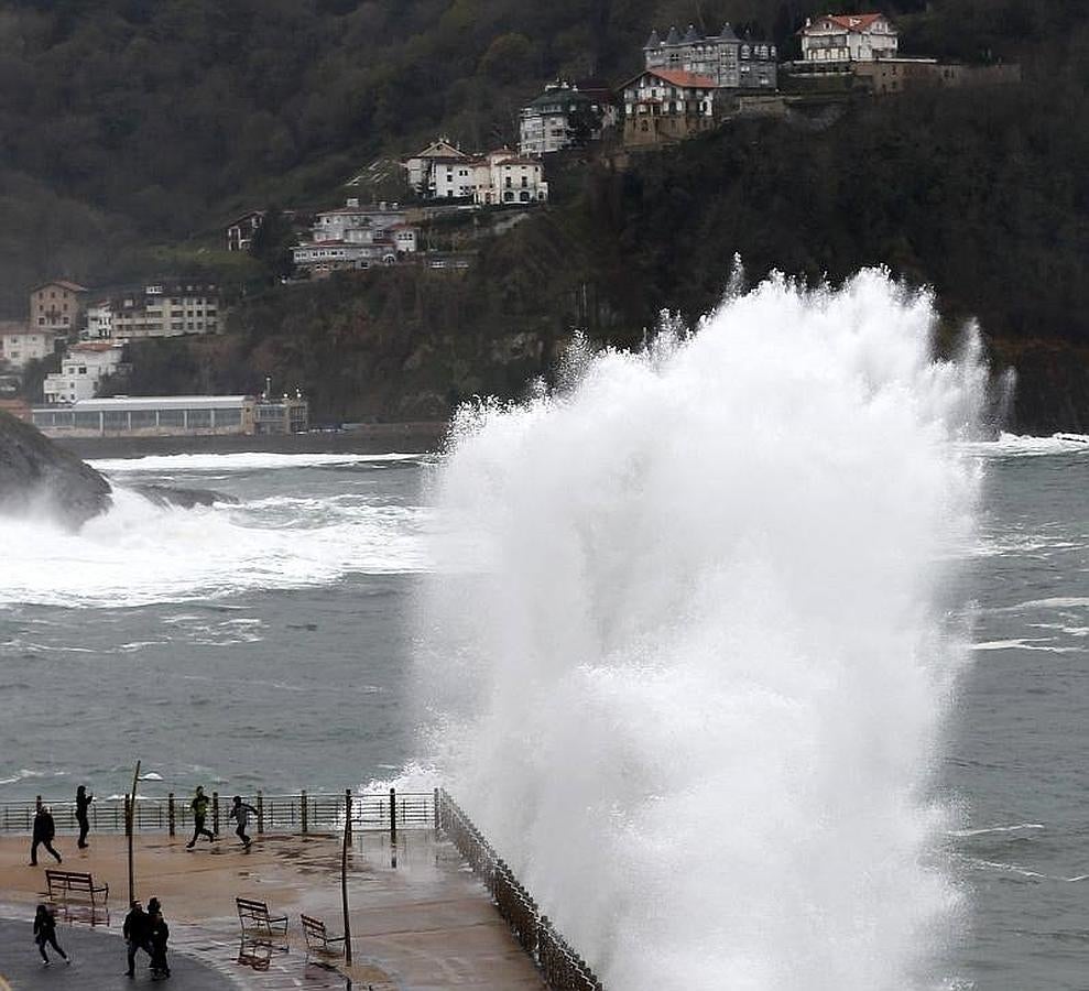 Varias personas huyen de una ola en el Paseo Nuevo de San Sebastián. 