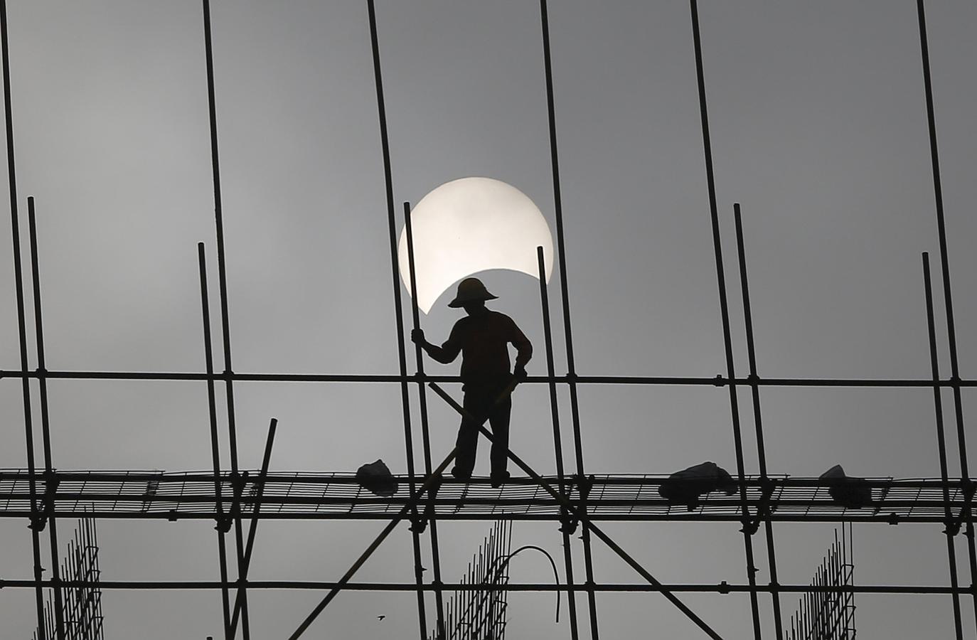 Un hombre trabaja con el eclipse parcial de sol de fondo en Camboya. 