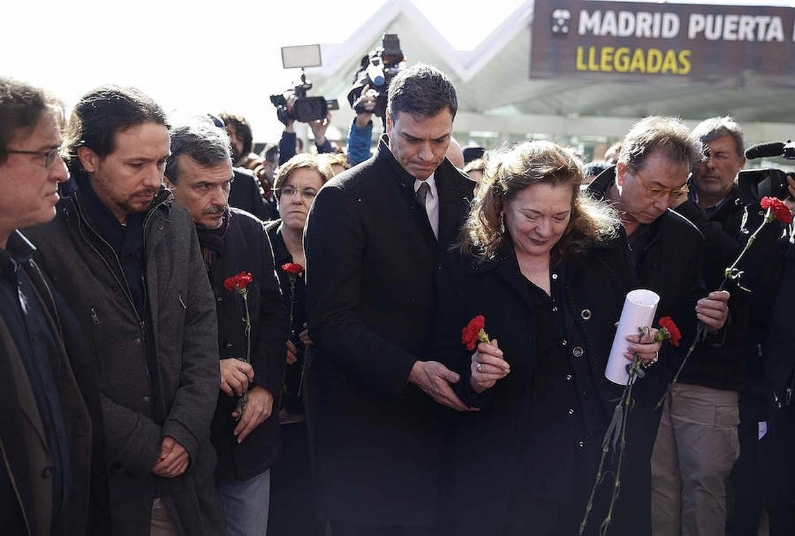 15.. Pilar Manjón se agacha a depositar las flores en el momumento del 11-M de Atocha con la ayuda del líder del PSOE, Pedro Sanchez