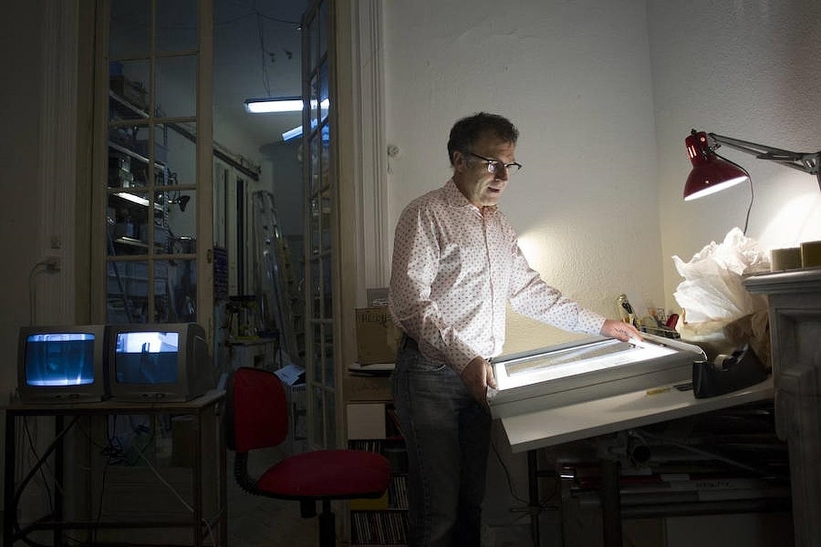Maté manipula una de sus cajas de luz en su despacho. Al fondo, vista de su almacén. 