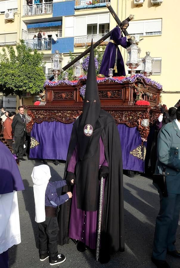 Un nazareno de la Hermandad del Divino Perdón de Alcosa frente a su Cristo