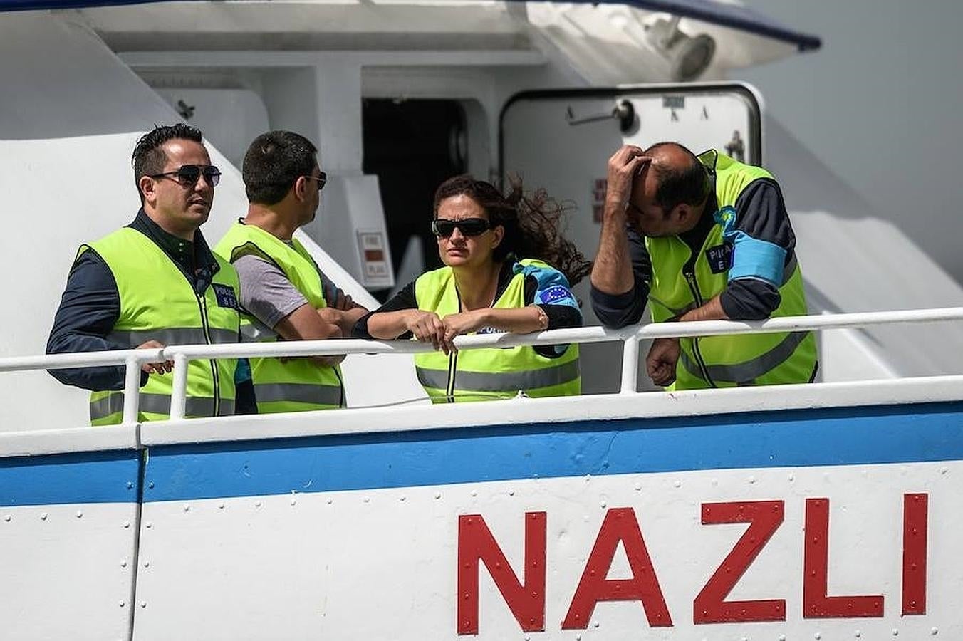 Oficiales de Frontex en Grecia miran desde su barco como son trasladados los refugiados en un ferry a Turquía. 