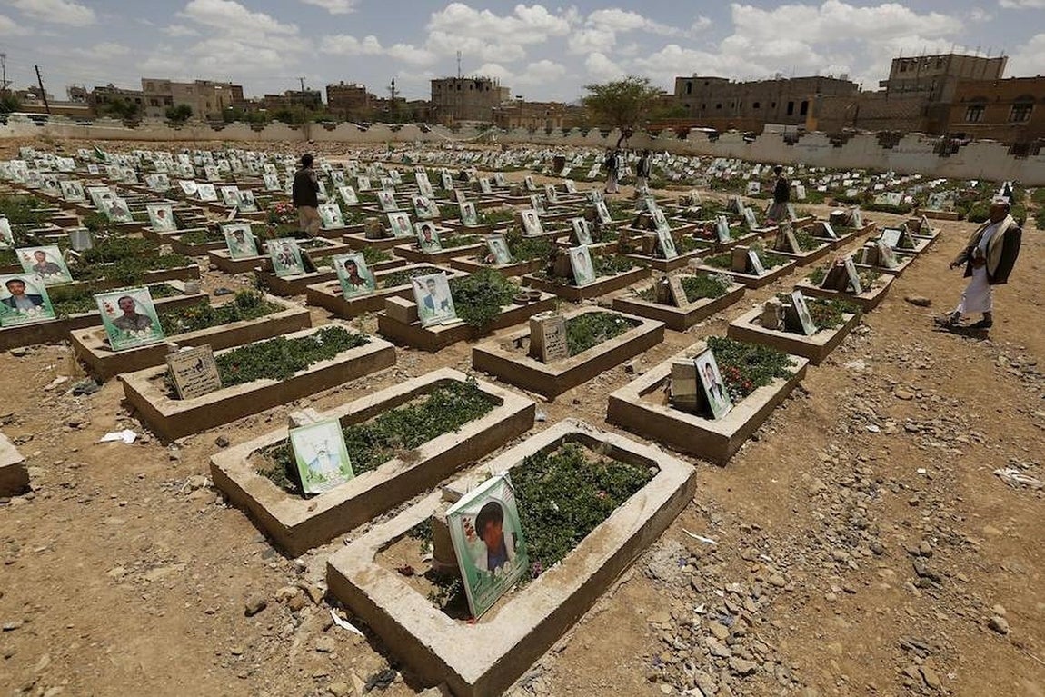 Varias personas pasean por un cementerio de luchadores hutíes fallecidos en combates durante la guerra de Yemen. 