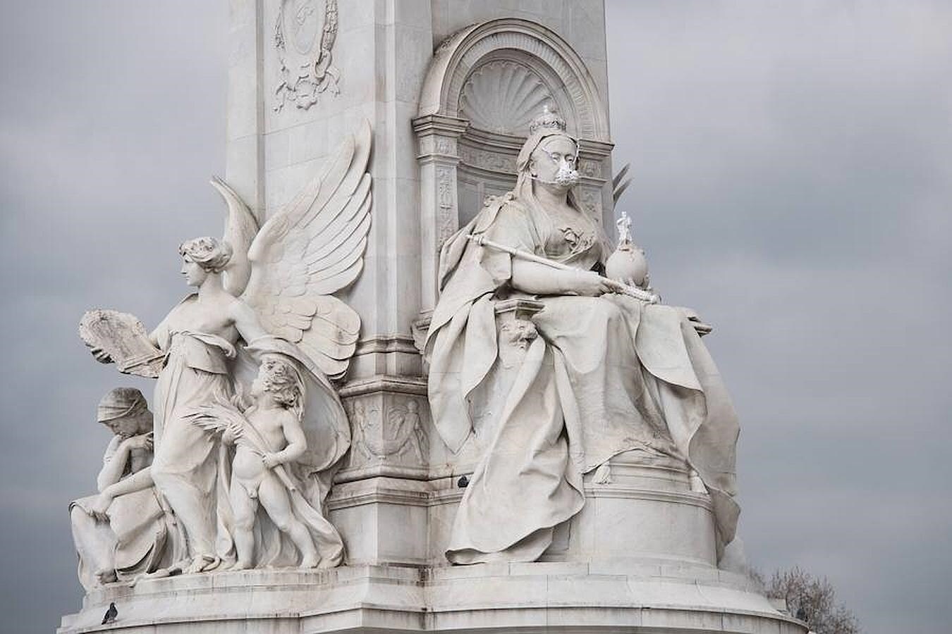 Miembros de Greenpeace ponen una mascarilla a la estatua de Reina Victoria. 
