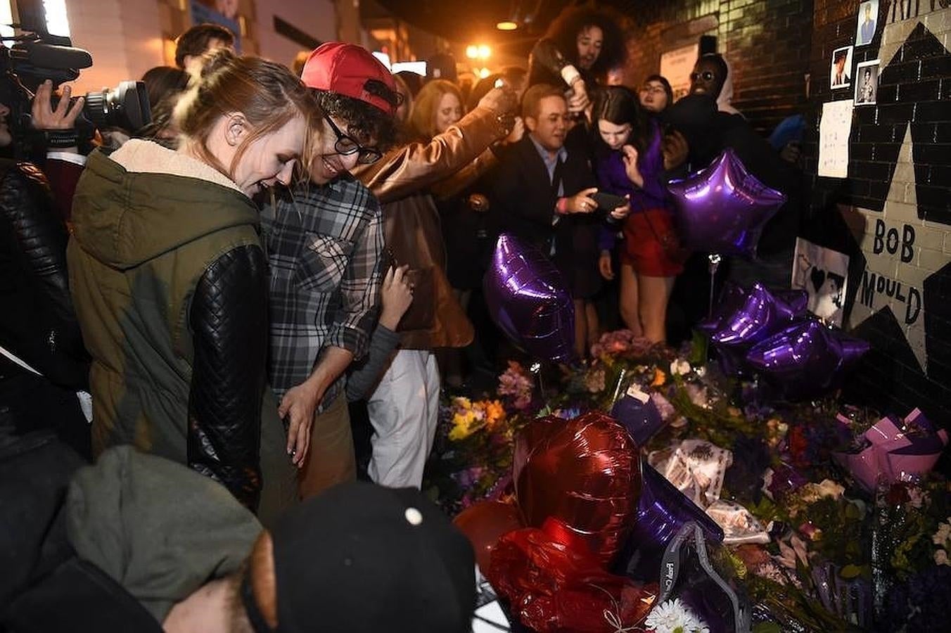 Una mulltitud pone mensajes, flores y velas en la puerta del club First Avenue, en Minneapolis